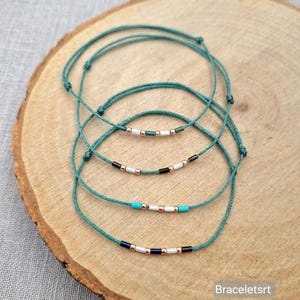 Könnte beinhalten: Eine weiße Keramik-Tasse mit schwarzem Henkel und dem Text "But first, coffee" in schwarzer, handschriftlicher Schrift. Die Tasse steht auf einer weißen Oberfläche.