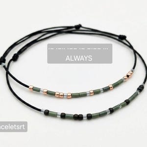 Peut inclure: Deux bracelets en cordon noir avec des perles vert olive et or rose. Un bracelet porte le mot "ALWAYS" dans un rectangle gris. Le mot "Braceletsrt" est dans un rectangle blanc.