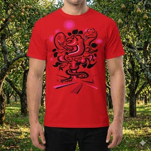 May include: A red t-shirt with a graphic design. The design features a central, abstract figure in shades of red and black, with pink accents and a swirling, snake-like form. The t-shirt is short-sleeved.