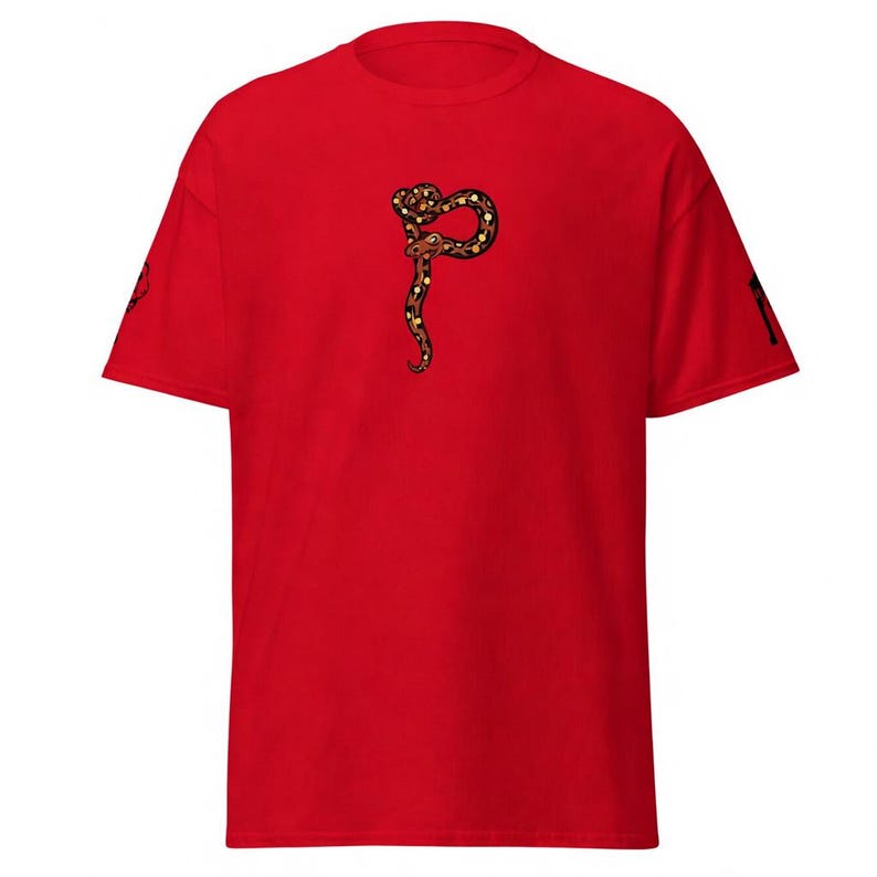 May include: A vibrant red t-shirt with a detailed illustration of a snake in brown, black, and yellow. The snake is coiled in a stylized design. The shirt has short sleeves and a crew neck.