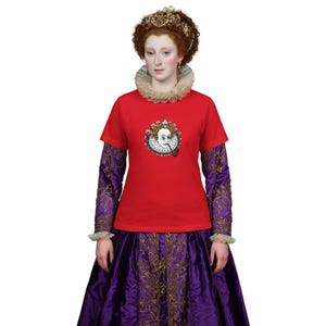 Może przedstawiać: Osoba nosząca czerwoną koszulkę z grafiką historycznej postaci palącej fajkę. Osoba nosi również wysadzaną klejnotami koronę, plisowany kołnierz oraz fioletowo-złotą suknię. Tło jest białe.