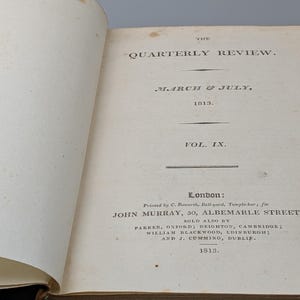 Op de afbeelding: Een open antiek boek met de titel The Quarterly Review, March & July, 1813, Vol. IX. De crèmekleurige pagina's bevatten zwarte gedrukte tekst met publicatiegegevens, waaronder Londen, John Murray, 50 Albemarle Street en het jaartal 1813.