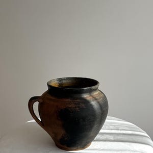 Maceta antigua de arcilla negra y terracota.