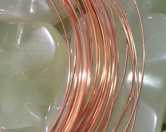 May include: A close-up of a coil of copper wire, with a shiny, metallic finish. The wire is wound tightly together, creating a circular shape. The wire is resting on a white, textured surface.