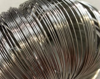 May include: A close-up of a silver metal coil of wire. The wire is tightly wound and forms a spiral shape.