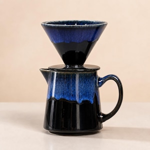 May include: A ceramic pour-over coffee maker set with a dark blue and black glaze. The set includes a cone-shaped dripper, a lid, and a carafe with a handle. The coffee maker is designed for manual brewing.