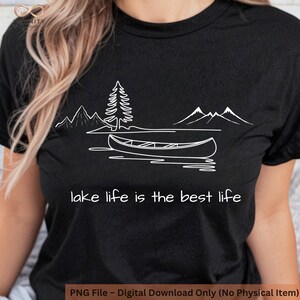 Könnte beinhalten: Schwarzes T-Shirt mit einer weißen Grafik einer See-Szene, einschließlich Berge, einem Kanu und einem Kiefernbaum. Der Text "lake life is the best life" steht darunter. Digitaler Download.