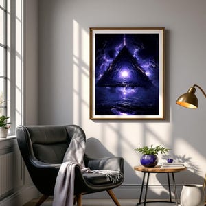 May include: A framed art print depicts a surreal, triangular portal scene with a bright light at the center. The artwork is framed in gold and hangs on a gray wall above a black leather armchair. A gray throw blanket is draped over the chair.