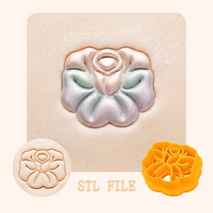 May include: A floral design, possibly a rose, is embossed on a light-colored surface. The image includes a stamp of the design, a 3D-printed orange cutter, and the text "STL FILE". The embossed design has a pearlescent finish with pink, blue, and green hues.