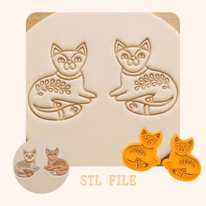 Op de afbeelding: Een set katvormige koekjessnijders en afdrukken. Het ontwerp toont twee kattenafdrukken op een lichtbeige oppervlak, met twee oranje snijders en twee kleinere afdrukken eronder. De tekst "STL FILE" staat onderaan afgedrukt.