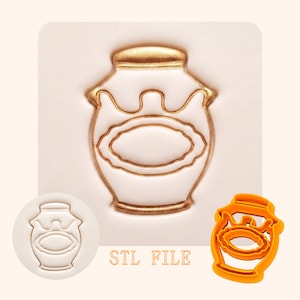 May include: A white and gold honey pot design, with a gold lid and trim, and a gold oval in the center. The image includes a 3D-printed orange plastic cookie cutter of the same design, and a stamp of the design. The text "STL FILE" is also present.