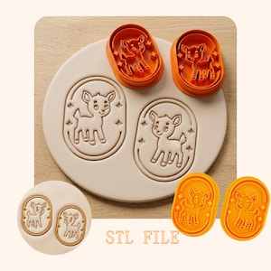 Può includere: Tagliapasta in plastica arancione e un timbro beige con un disegno di cervo. Il timbro ha due immagini di cervo all'interno di una cornice ovale con accenti di stelle. I tagliapasta hanno lo stesso disegno di cervo. Il testo "STL FILE" è visibile.