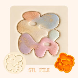 May include: A digital file for 3D printing featuring an abstract, organic shape with multiple rounded lobes and two internal cutouts. The design is displayed in a multi-colored, textured finish, a plain white version, and a solid orange version with text STL FILE.