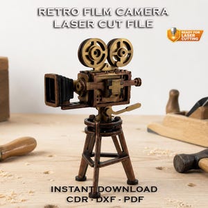 Op de afbeelding: Een gedetailleerd, miniatuur retro filmcameramodel in tinten brons en bruin, gemonteerd op een statief. De afbeelding bevat de tekst "RETRO FILM CAMERA LASER CUT FILE" en "INSTANT DOWNLOAD CDR-DXF-PDF".