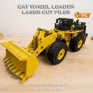 Könnte beinhalten: Ein gelbes Holzmodell eines Cat-Radladers mit schwarzen Reifen und einer Frontschaufel. Das Modell trägt den Text "CAT WHEEL LOADER LASER CUT FILES" und "INSTANT DOWNLOAD DXF CDR PDF". Ein kleines Logo lautet "READY FOR LASER CUTTING".