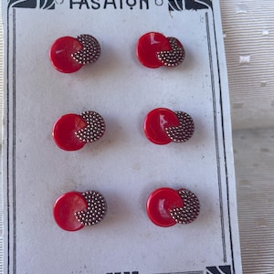 Op de afbeelding: Zes vintage rode en zilverkleurige knopen op een witte kaart. Elke knoop heeft een ronde rode basis met een getextureerde zilverkleurige accent. De kaart leest "THE FASHION" in zwarte tekst.