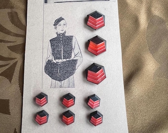 May include: A collection of geometric buttons with a black and red layered design. The buttons are arranged on a card with the text "Haute Mode" and a vintage fashion illustration. The buttons are likely for sewing or crafting.