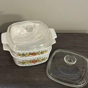 May include: Two square white glass casserole dishes with integrated side handles and clear glass lids. The dishes feature a colourful botanical print of vegetables and herbs with the text Le Persil, Les Sauges printed on the front of the base.