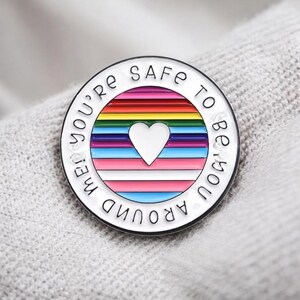 Peut inclure: Une tasse en c&eacute;ramique blanche avec une anse noire et le texte "But First, Coffee" en gras noir. La tasse est pos&eacute;e sur une surface en bois. La tasse mesure environ 10 cm de haut.