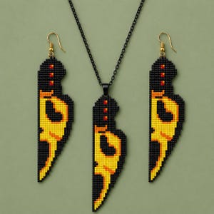 May include: A jewelry set consisting of a necklace and two matching earrings, each featuring a pixelated knife design crafted from black, yellow, and orange beads. The necklace hangs on a thin black chain, while the earrings have gold-tone hooks.