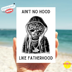 以下が含まれることがあります： サングラスとパーカーを着た猫の白黒イラストで、「AIN'T NO HOOD LIKE FATHERHOOD」というテキストが入っています。「Download Now」ステッカーと「Seaside Graphics」のロゴも含まれています。