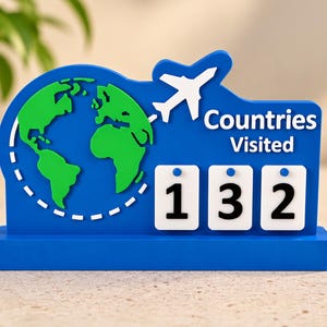 May include: A blue desktop display featuring a green globe graphic, a white aeroplane silhouette, and the text "Countries Visited" above three white square tiles displaying the black numbers 1, 3, and 2 on a solid blue rectangular base.