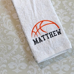 May include: White towel with an orange basketball and the name "MATTHEW" embroidered in black.
