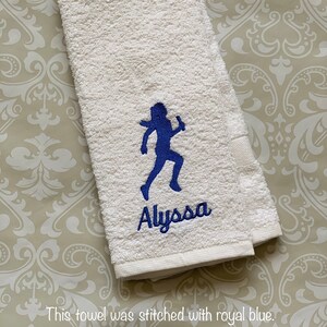 May include: White towel with a blue running girl silhouette and the name "Alyssa" embroidered in blue.
