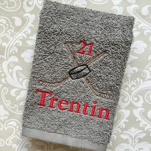 May include: Gray towel with red embroidery of a hockey stick and puck with the number 21 and the name Trentin.