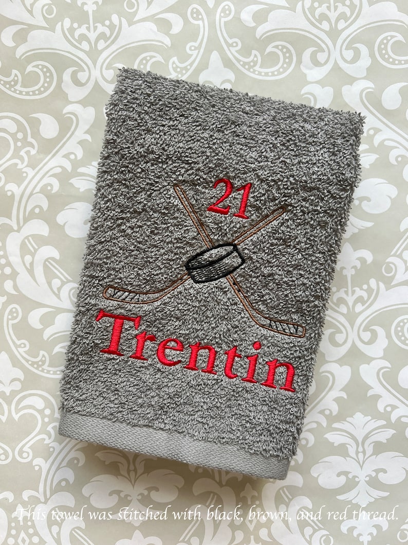May include: Gray towel with red embroidery of a hockey stick and puck with the number 21 and the name Trentin.