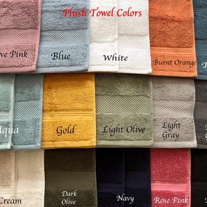 May include: A collection of plush towels in various colors, including mauve pink, blue, white, burnt orange, teal, aqua, gold, light olive, light gray, dark gray, cream, dark olive, navy, rose pink, and black. The towels are arranged in two rows, with the colors labeled below each towel.