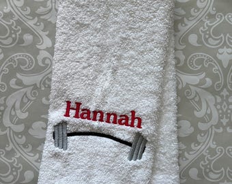 Könnte beinhalten: Weißes Handtuch mit dem Namen "Hannah" in rot und einer Hantel in grau und schwarz gestickt.