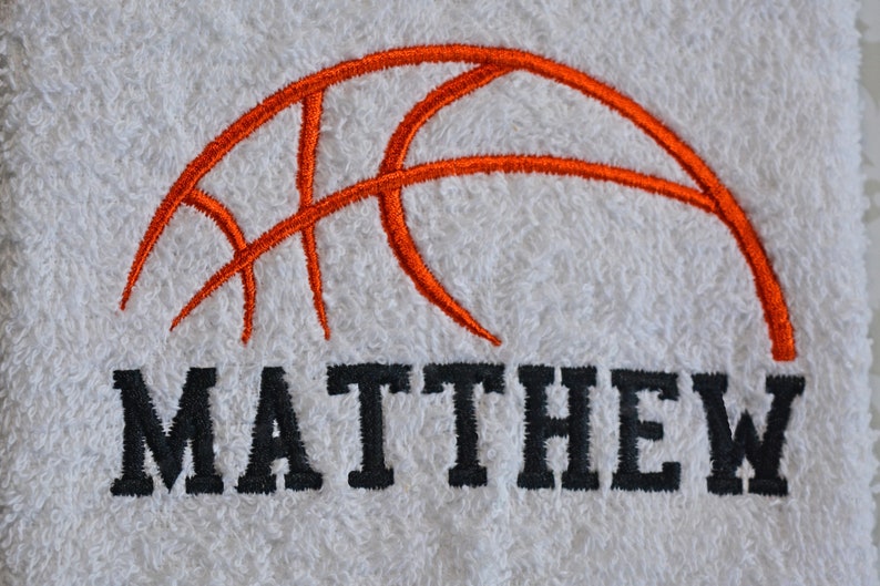 May include: White towel with an orange embroidered basketball and the name "MATTHEW" in black embroidery.