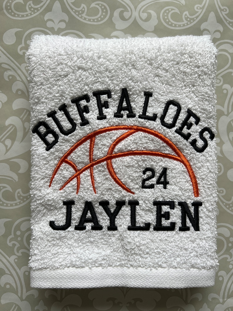 May include: White towel with black embroidered text "Buffaloes" and "Jaylen" with a basketball graphic and the number "24" in orange.