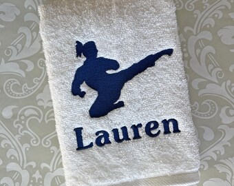 May include: White hand towel with a navy blue silhouette of a person performing a martial arts kick. The name "Lauren" is embroidered in navy blue. The text "This towel is stitched with navy thread" is at the bottom.