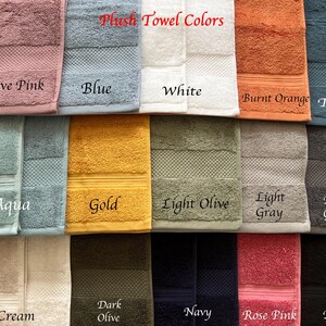 May include: A collection of plush towels in various colors, including mauve pink, blue, white, burnt orange, teal, aqua, gold, light olive, light gray, dark gray, cream, dark olive, navy, rose pink, and black. The towels are arranged in two rows, with the colors labeled below each towel.