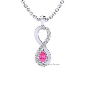 Könnte beinhalten: Eine silberfarbene Unendlichkeits-Halskette mit einem birnenförmigen rosa Edelstein in einer der Schlaufen. Das Unendlichkeitssymbol ist an einer Seite mit kleinen, klaren runden Steinen besetzt und hängt an einer zarten silberfarbenen Gliederkette.