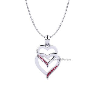 May include: A silver-toned necklace featuring a pendant with two overlapping heart shapes. The lower heart is accented with a row of small, vibrant red stones along one side. The pendant hangs from a delicate silver-toned chain. Text reads VaaniJewelsDesigns.