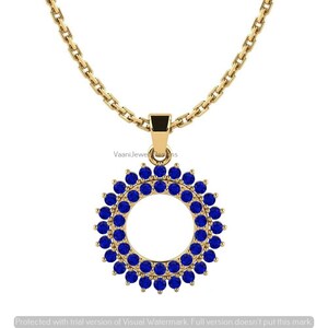Può includere: Una collana in oro con un ciondolo circolare decorato da due anelli concentrici di piccole pietre preziose blu, rotonde e vivaci. Il ciondolo è sospeso a una catena d'oro con maglie rettangolari, creando un gioiello luminoso e simmetrico.