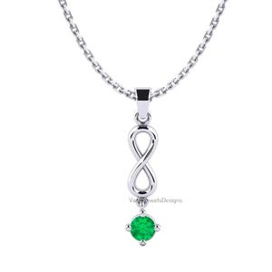 May include: A silver-toned necklace featuring a vertical infinity symbol pendant suspended from a delicate chain. A single round, vibrant green gemstone is set at the base of the infinity charm. The text VadoJewelsDesigns is visible near the pendant.