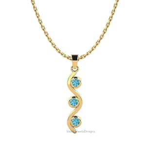 Könnte beinhalten: Eine goldene Anhängerkette mit einem vertikalen, gewellten Metallstab, der mit drei runden, hellblauen Edelsteinen besetzt ist. Der Anhänger hängt an einer zarten Goldkette und der Text VaaniJewelsDesigns ist am unteren Bildrand zu sehen.