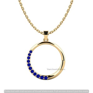 May include: A gold chain necklace featuring a circular pendant. The pendant is a smooth gold ring with a series of small, round, deep blue gemstones set along the left side of the circle. The text VaaniJewelsDesigns is visible on the pendant.