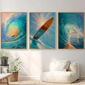 Puede incluir: Conjunto de tres impresiones artísticas enmarcadas que representan olas del océano y tablas de surf. La obra de arte presenta vibrantes tonos turquesa, azul y naranja, con una tabla de surf en el aire. Las pinturas están en marcos de madera, creando un tema costero.