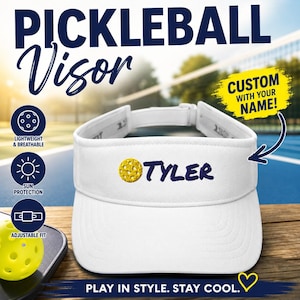 May include: A white visor featuring an embroidered yellow pickleball icon and the name Tyler in dark blue text. The visor has an adjustable strap at the back. Text on the image includes PICKLEBALL Visor, CUSTOM WITH YOUR NAME, and PLAY IN STYLE. STAY COOL.