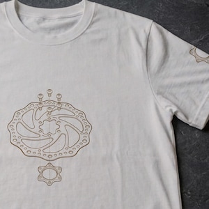 Könnte beinhalten: Weißes T-Shirt mit brauner Grafik einer Fahrrad-Scheibenbremse auf der Vorderseite. Die Ärmel haben passende braune Grafiken. Das T-Shirt hat einen Rundhalsausschnitt und kurze Ärmel.
