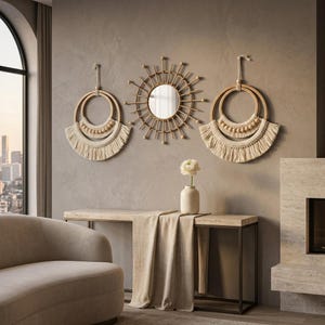 May include: Two circular wall hangings featuring cream-colored macrame fringe and wooden beads suspended from wooden hoops, flanking a central sunburst-style mirror with thin wooden spokes radiating from a circular glass center.