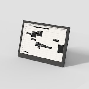 May include: A dark gray digital tablet displaying a weekly calendar with black rectangular blocks representing scheduled events. The screen shows dates from July 29th to August 4th. The tablet is angled slightly, showcasing its sleek design.