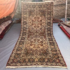 May include: A rectangular area rug featuring a dense, intricate floral and vine pattern in shades of deep red, black, and cream. The design includes two prominent central medallions and a wide, detailed border with fringe on the ends.