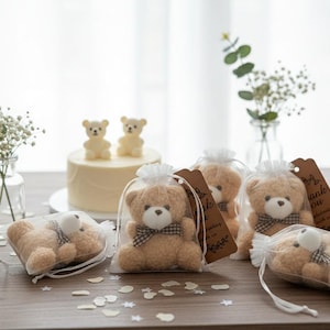 Op de afbeelding: Kleine beige pluche beren met witte snuiten en bruin-witte geruite strikjes, elk afzonderlijk verpakt in een doorzichtig wit organza zakje met een bruin papieren label waarop de woorden Thank You staan gedrukt.
