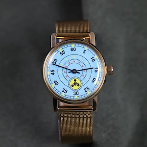 May include: A wristwatch with a gold-tone metal mesh band and a round gold-tone case. The light blue dial features black hour and minute hands, a black second hand, black numerals from 5 to 60, a 24-hour inner ring, and a yellow circular icon.